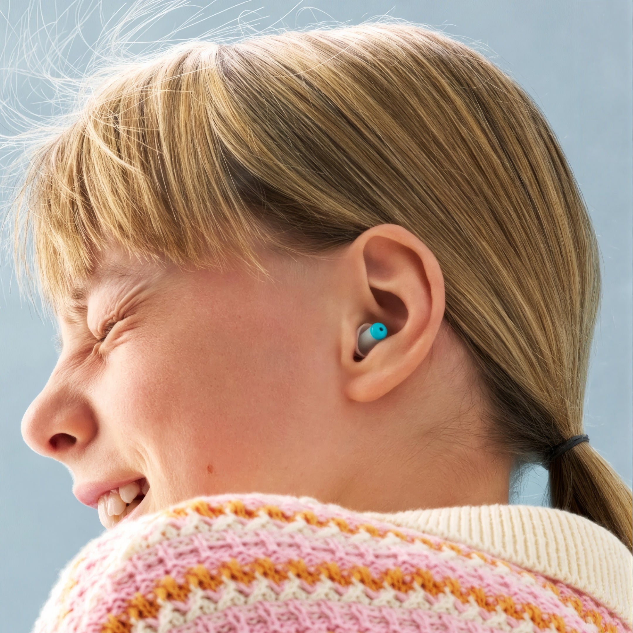 Smiling girl with blonde hair wearing an Alpine Pluggies Kids earplug
