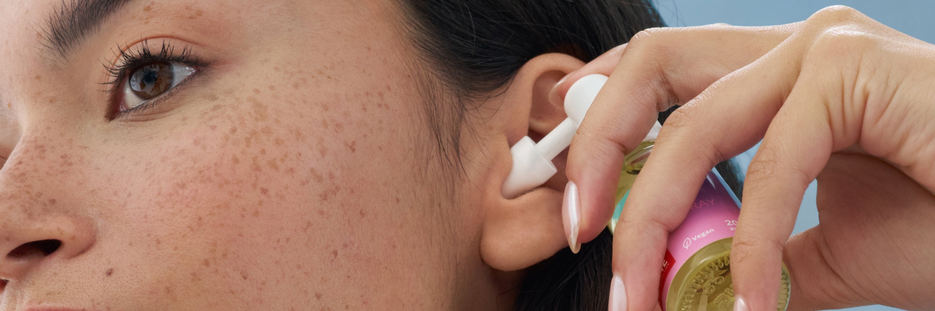 vrouw met orenspray bij het oor