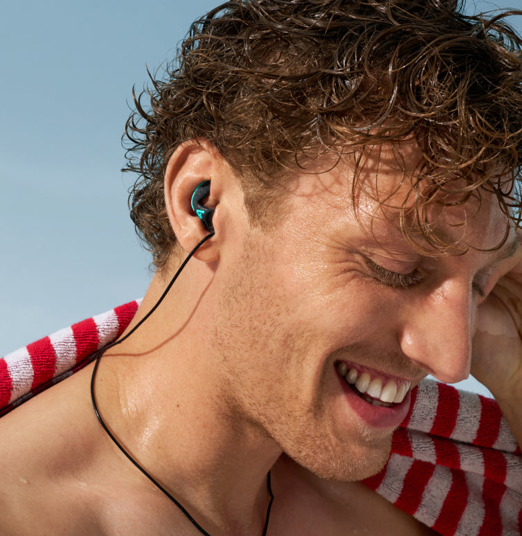 man met nat haar op de strand en alpine watersafe pro