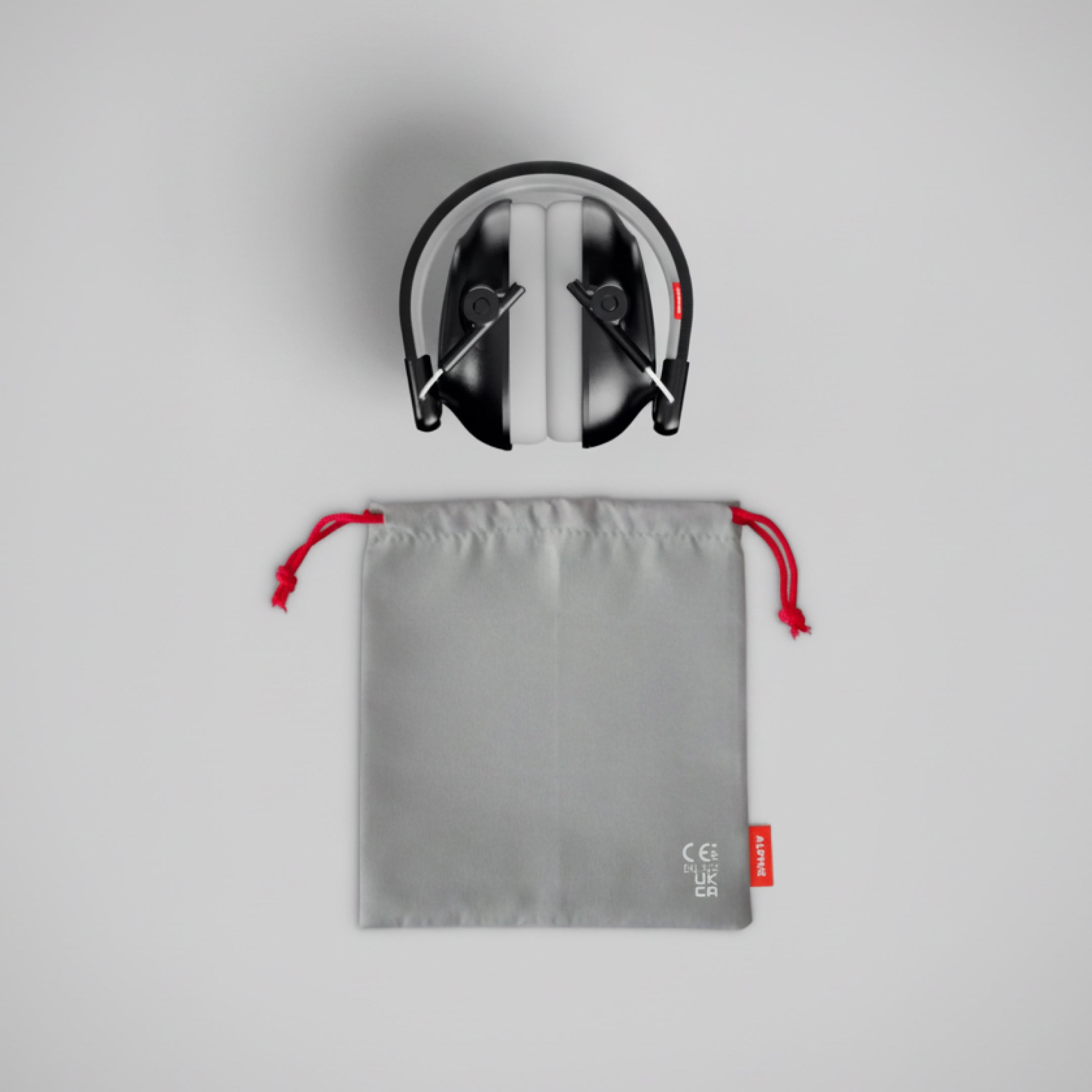 Alpine Muffy Baby ear defenders in black, folded, with grey carrying pouch 